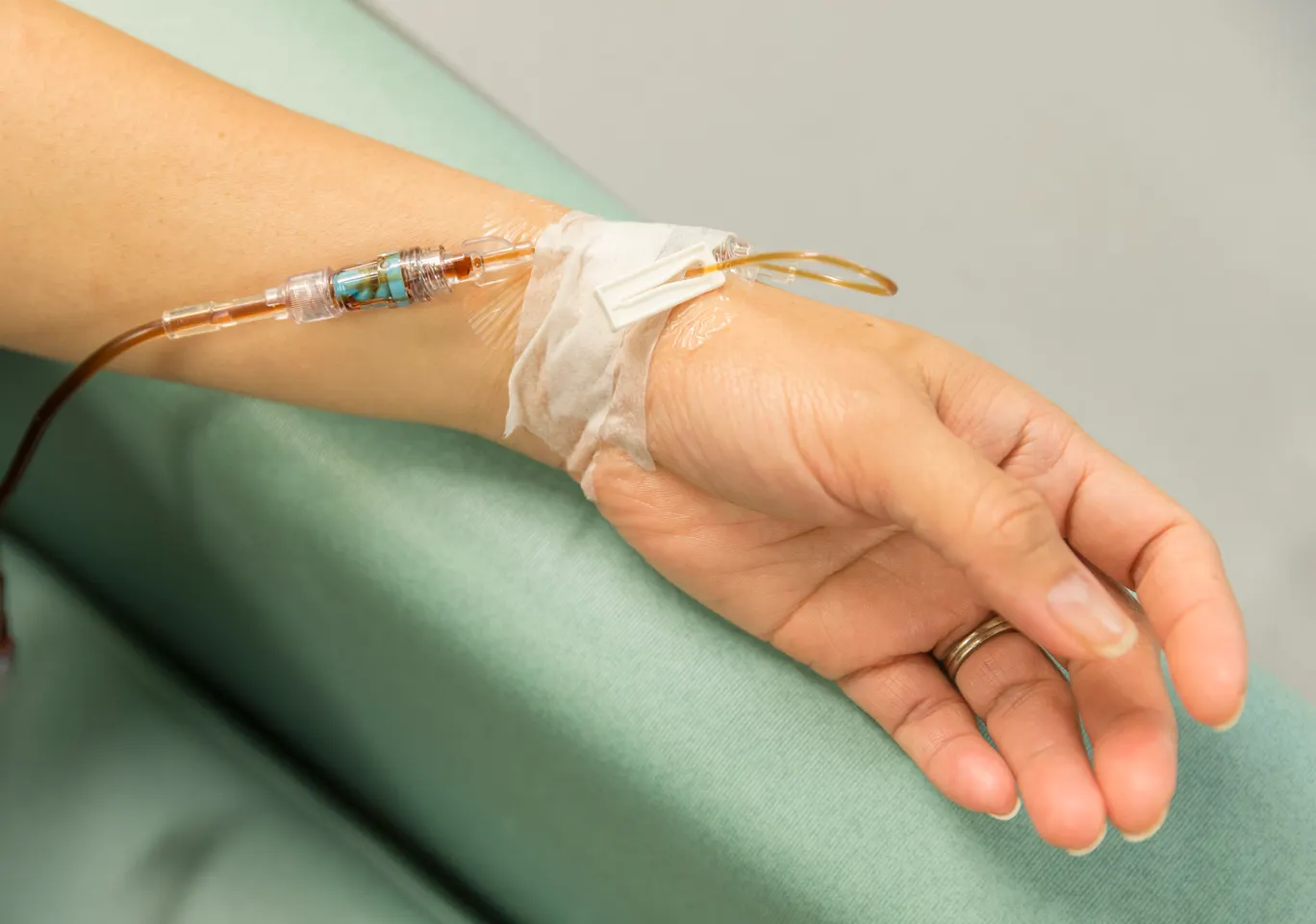Kroplówki witaminowe Częstochowa: dłoń z wenflonem i linią infuzyjną na podkładzie